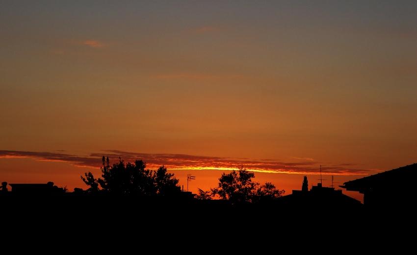 un tramonto sotto la riga in città foto di tramonti cittadino tra le case immagini al tramonto